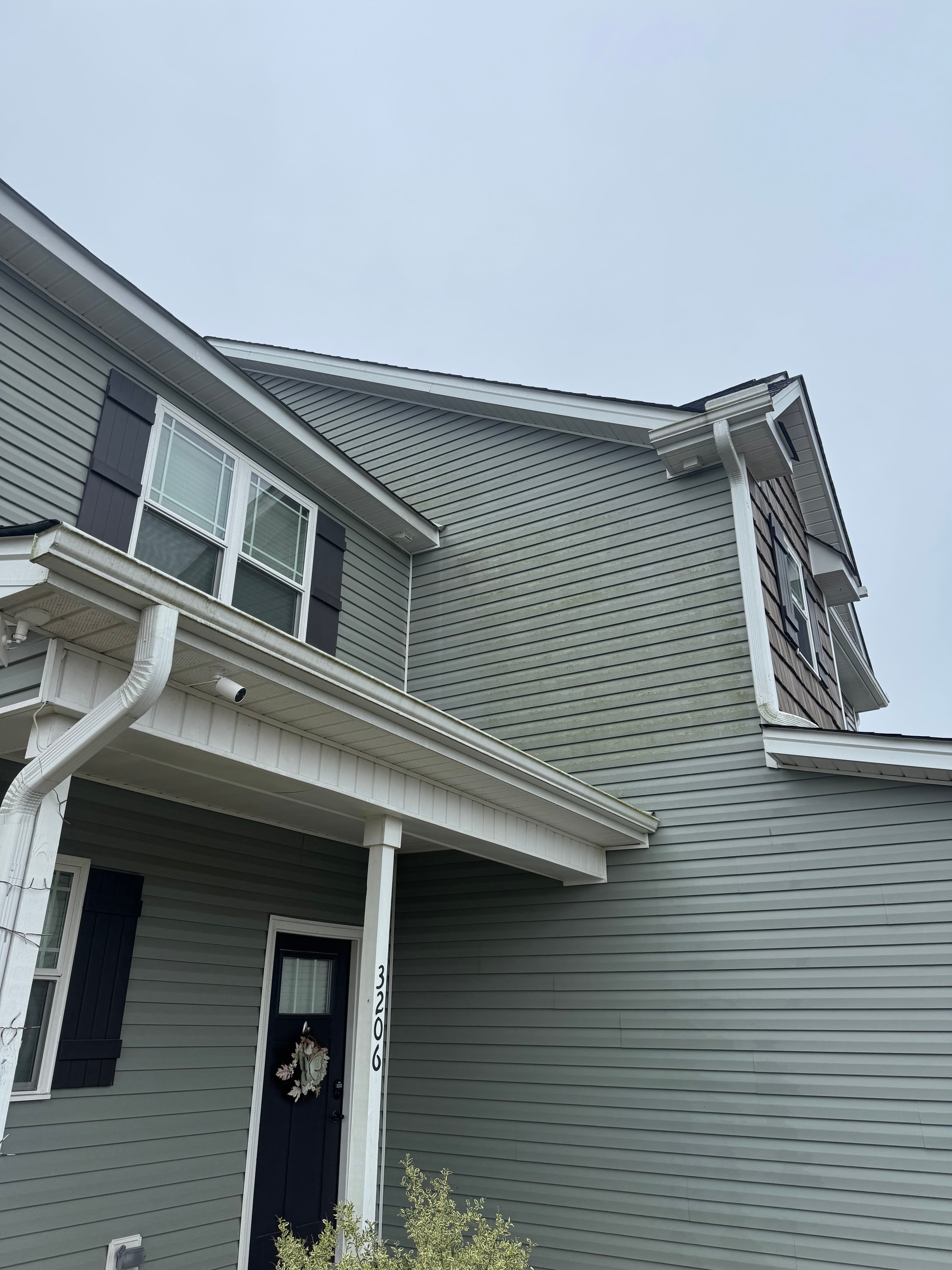 Before vinyl siding house wash in Fayetteville NC — green algae and mildew on exterior