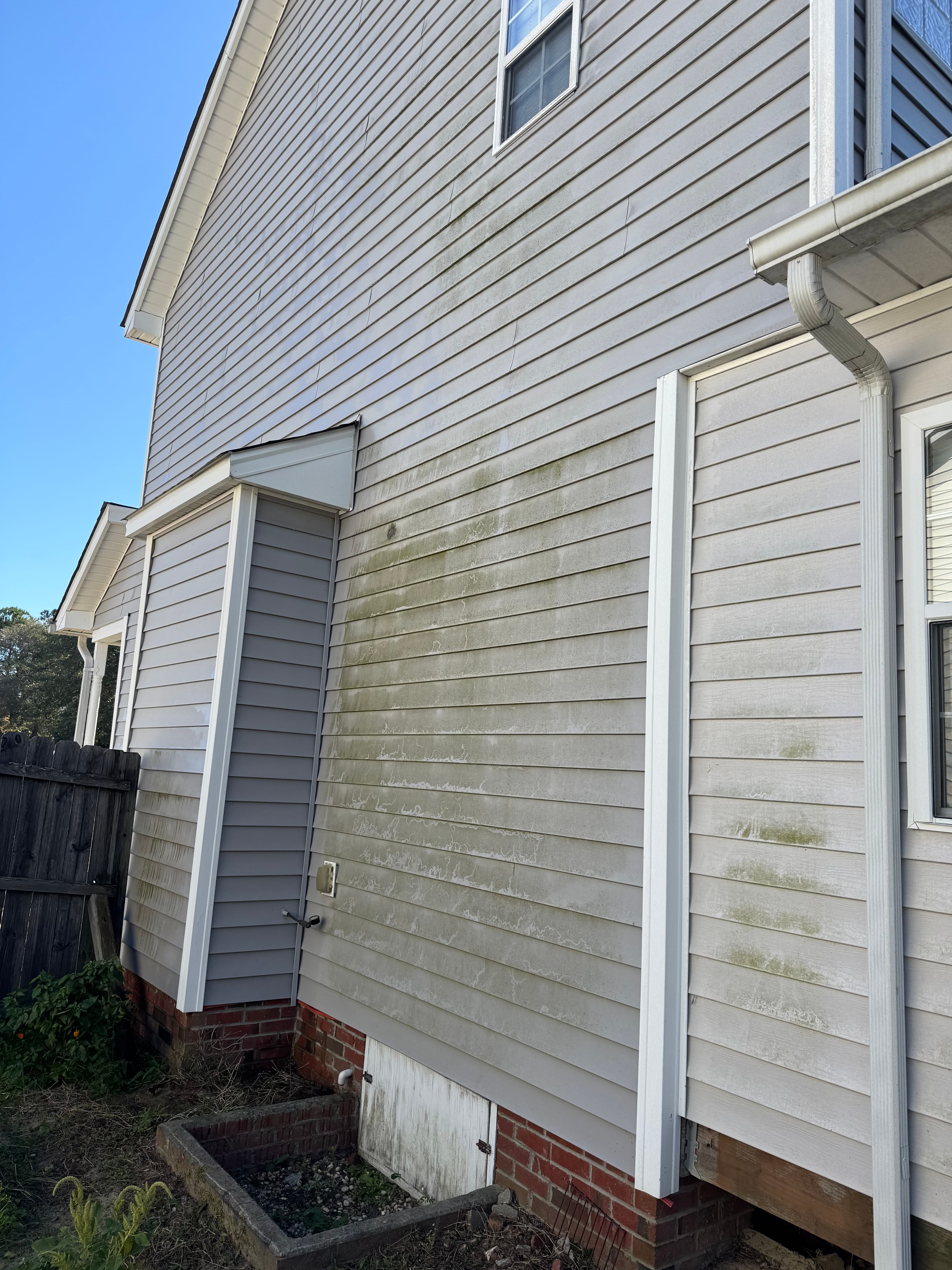 Home exterior with heavy green algae and mildew on vinyl siding in Fayetteville NC